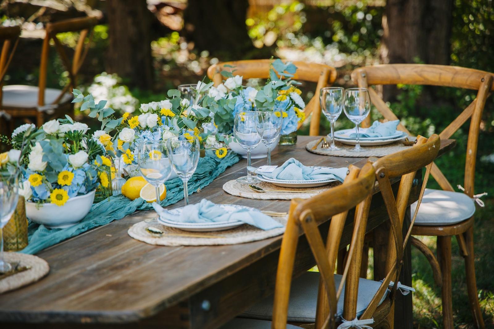 A long wooden table laid for a garden supper with lemons and green linen