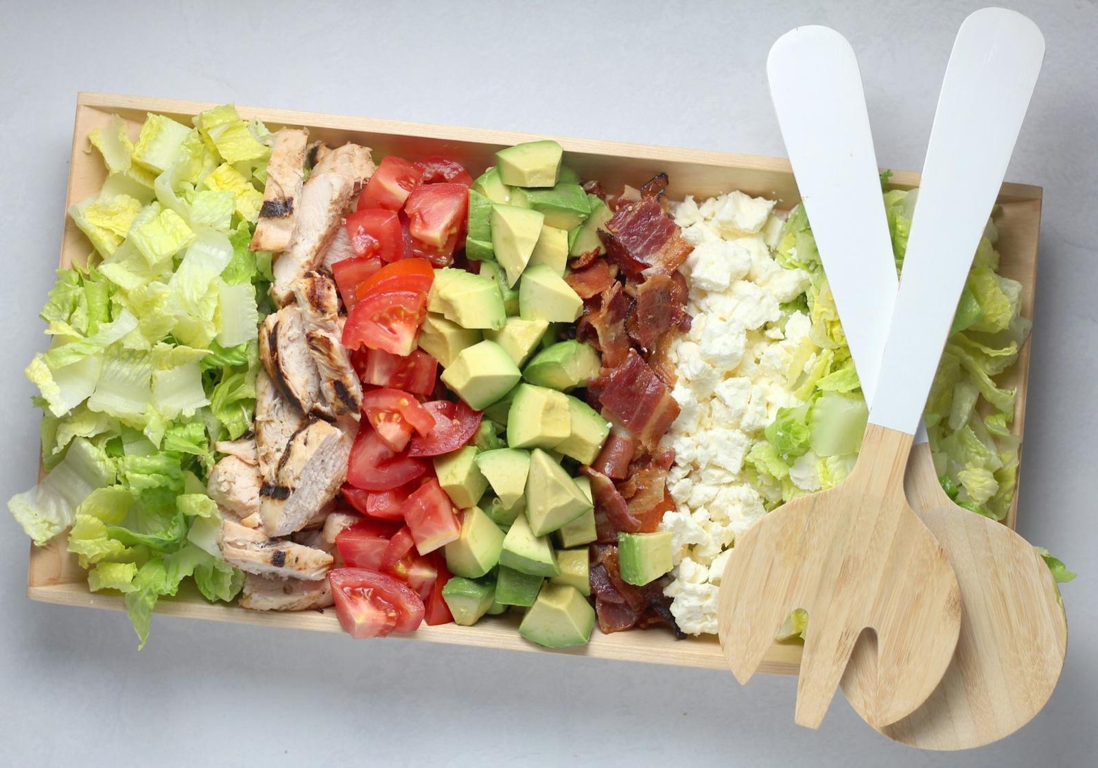 A tray of salad with chicken, avocado and egg in neat rows