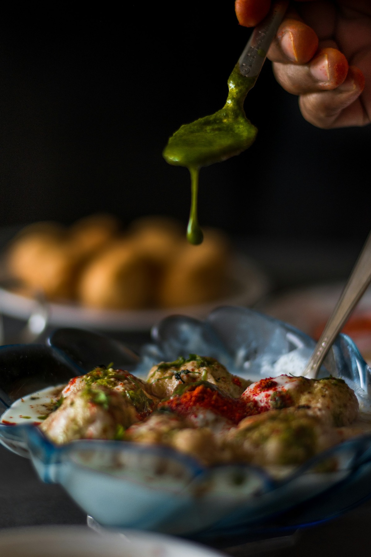 Green chutney being spooned over chaat