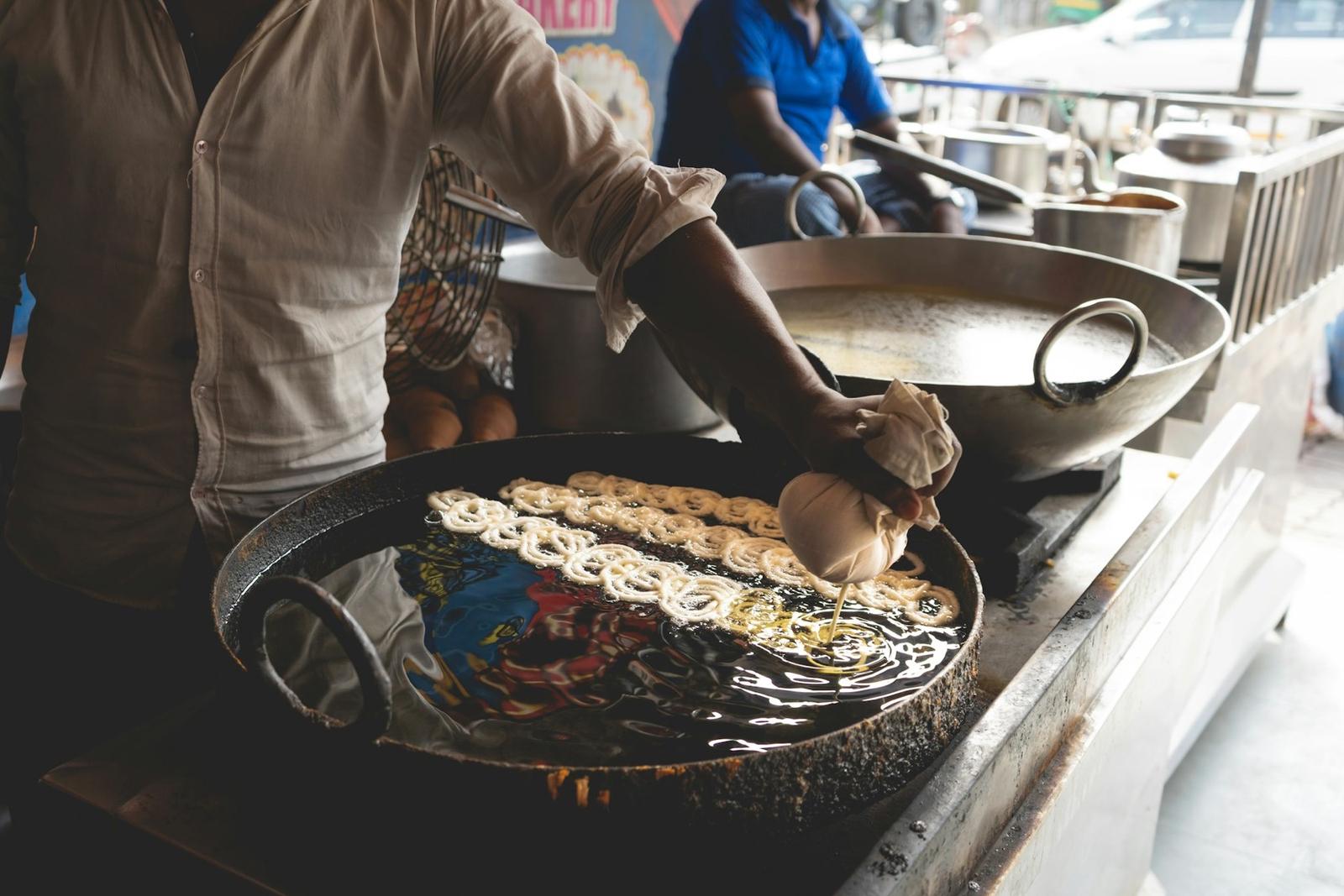 Jalebi batter being piped into hot oil