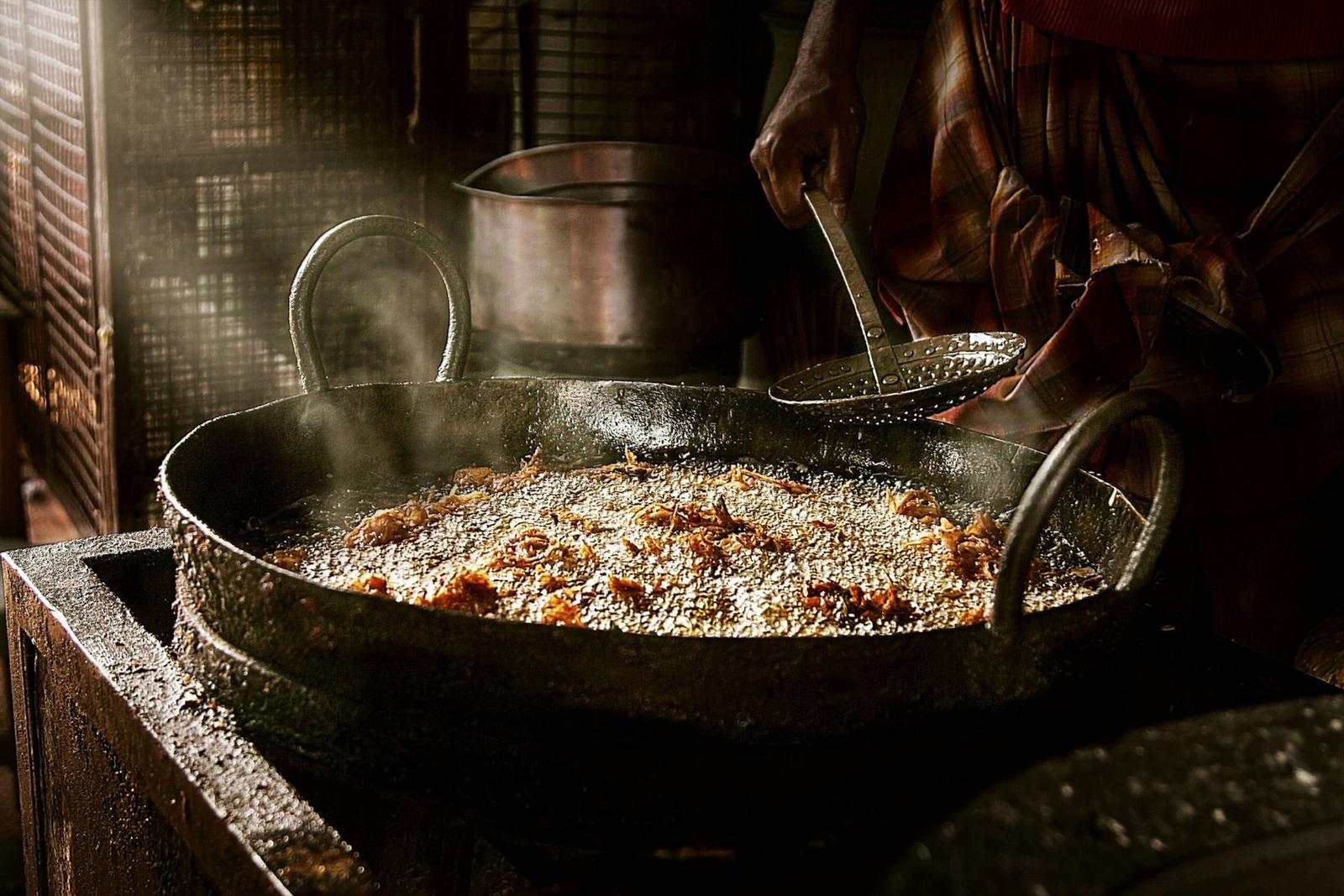 A deep kadai of oil over a flame