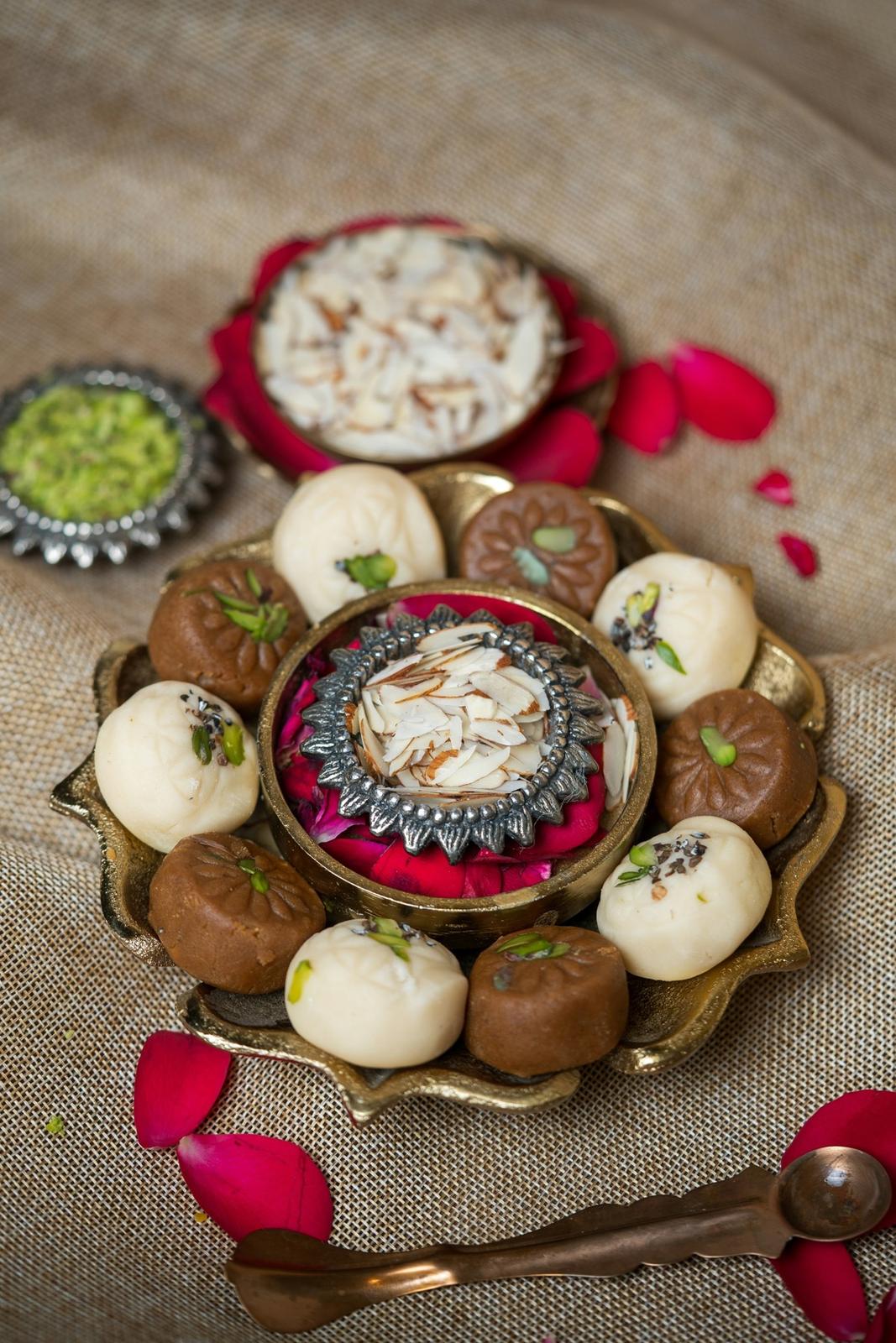 A brass thal of mithai with rose petals