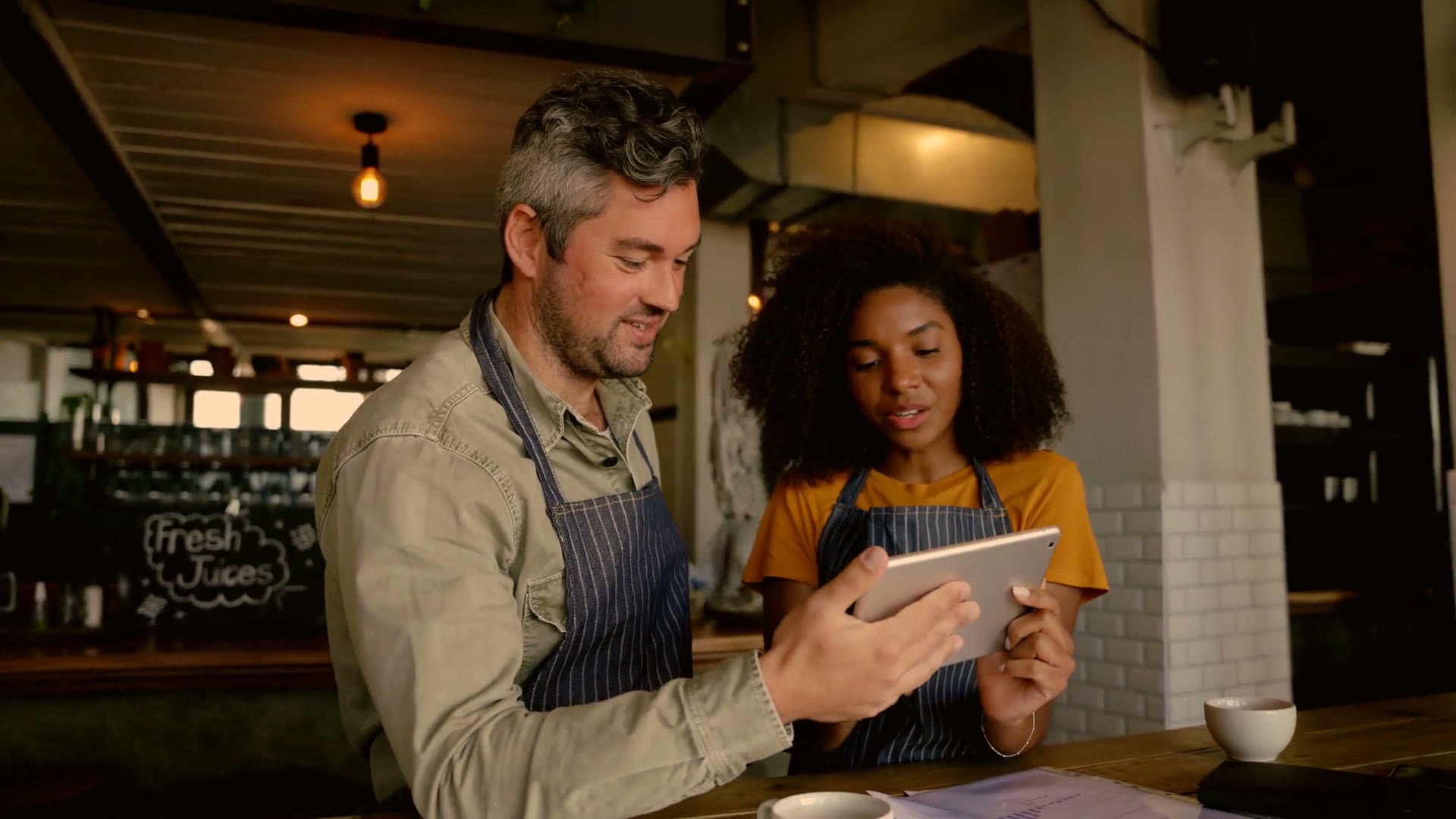 Café staff reviewing the day's orders together on a tablet